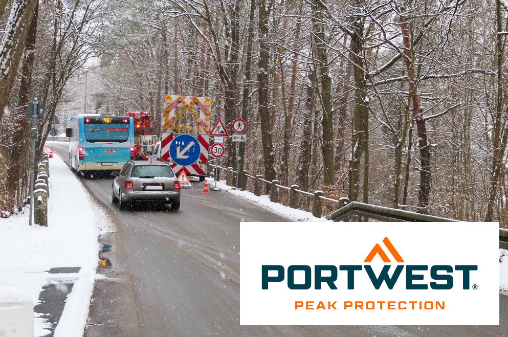 Scena di cantiere con autobus e auto su una strada innevata circondata da alberi. Nell'angolo destro c'è il logo del marchio Portwest. È presente un collegamento alla collezione di indumenti termici e frigoriferi.