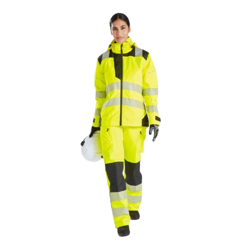 Donna con abbigliamento da lavoro giallo ad alta visibilit&agrave;. Tiene un casco in mano e guarda direttamente nella fotocamera. &Egrave; presente un link ai pantaloni antipioggia ad alta visibilit&agrave; PW3 da donna PW386.