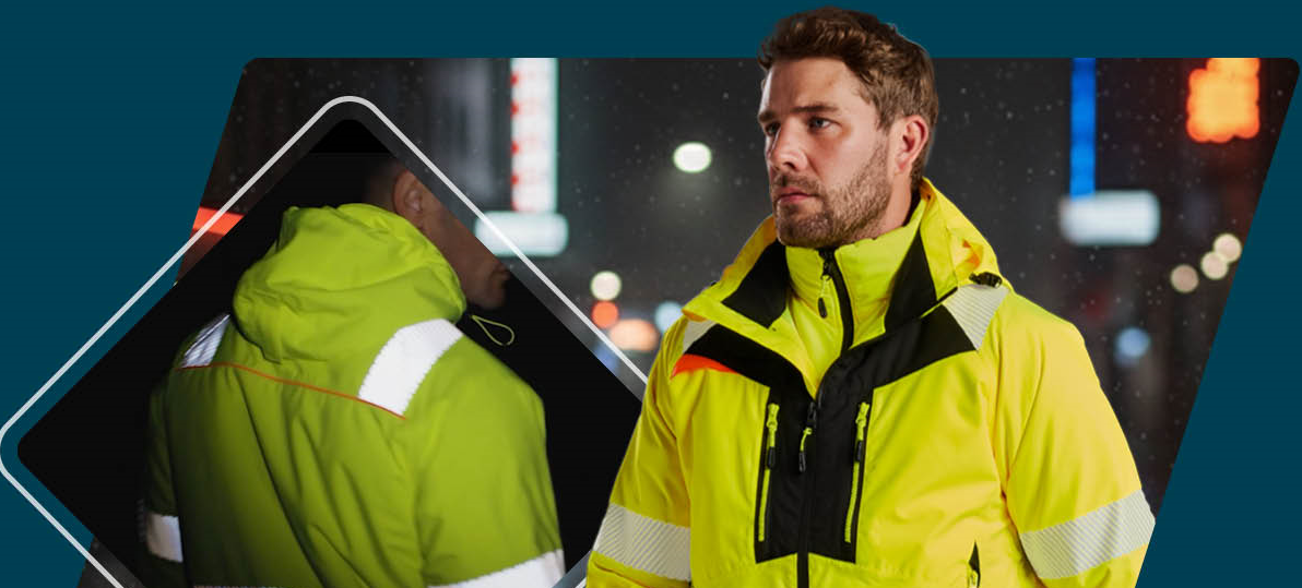 Un lavoratore con abbigliamento ad alta visibilit&agrave; giallo con strisce riflettenti e dettagli neri. Sullo sfondo, &egrave; visibile una strada buia con illuminazione sfocata. Il retro della giacca &egrave; mostrato a sinistra.