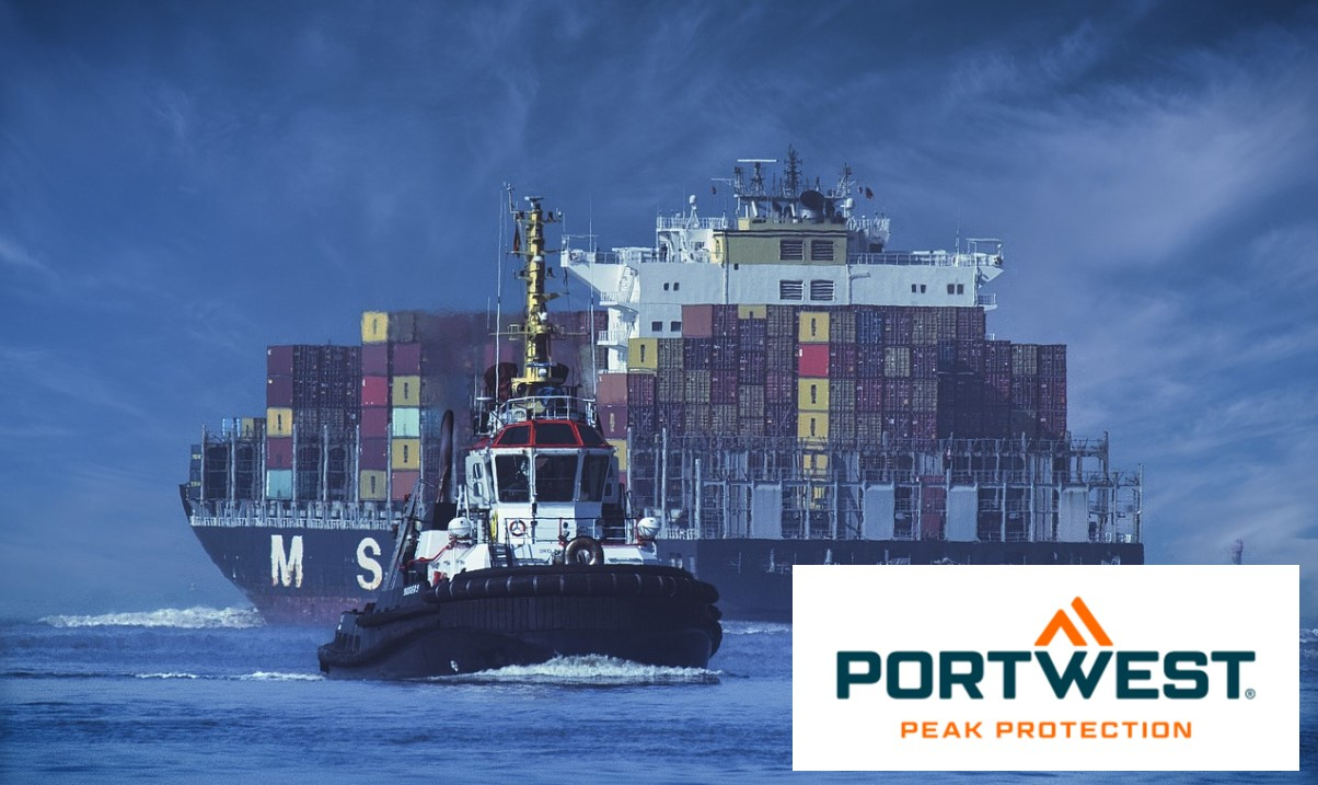 Una nave portacontainer che trasporta container colorati viene rimorchiata attraverso calme acque blu da un rimorchiatore. Il cielo è di un blu intenso e il logo Portwest è visualizzato in basso a destra. Viene fornito un collegamento alla raccolta di indumenti idonei alla navigazione.