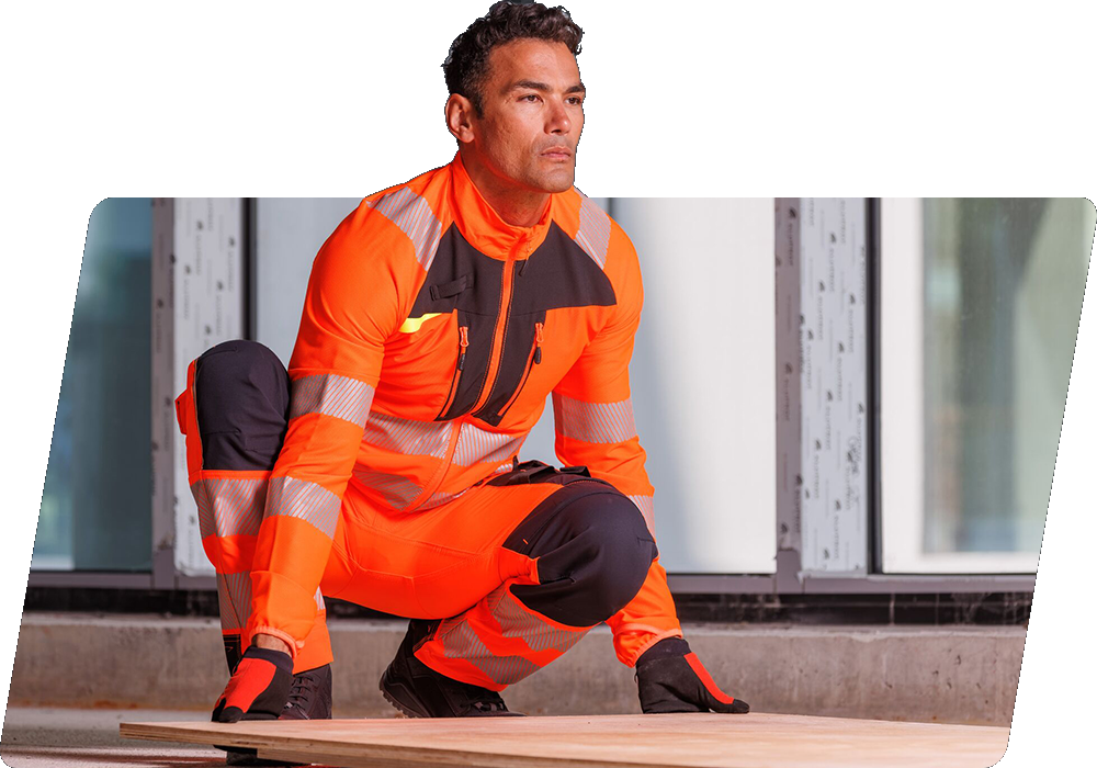 Un operaio dai capelli scuri con indumenti ad alta visibilità arancioni solleva un pannello di legno da terra. C'è un collegamento alla nostra collezione DX4.