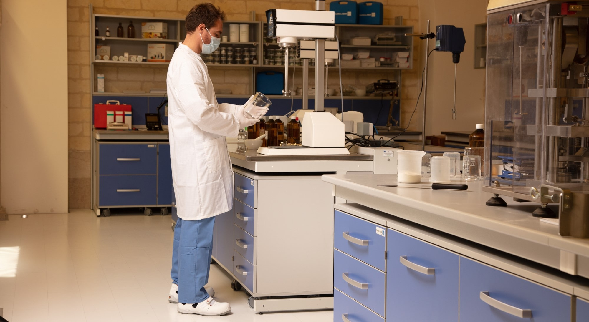 Tecnico di laboratorio in camice bianco e abbigliamento protettivo antistatico al lavoro in laboratorio con collegamento collegato al camice da lavoro antistatico.